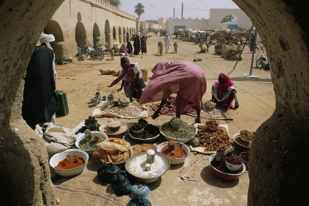 @GeorgeSteinmetz/NationalGeographic Dried spices and staples like garlic, peanuts, onions, pepper, salt, & okra are popular items in the open-air market of Faya Largeau.  Women here prefer the veils of the Moslem world, but in the bright colors of tropical Africa.  The buildings in the old market are made of mud-brick, with arches in the shape of a keyhole.